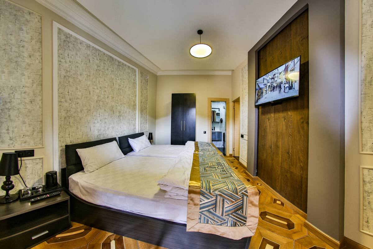 Ein Hotelzimmer mit einem großen Bett, einem an der Wand montierten Fernseher und Holzboden.