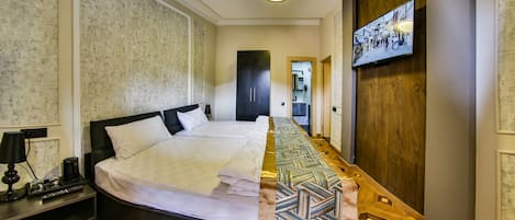 Una habitación de hotel con una cama grande, un televisor montado en la pared y suelo de madera.