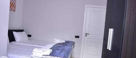 A bedroom with a bed, a wardrobe, a radiator, and a wall art piece.