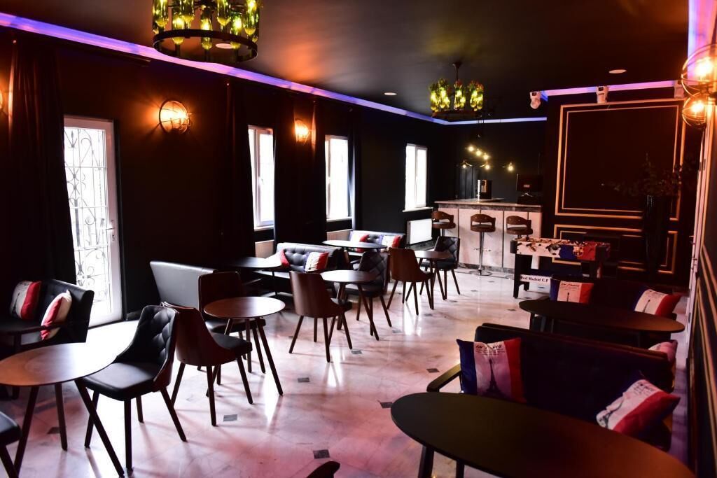 A modern lounge area with multiple seating options including sofas and tables, a bar area, and decorative lighting.