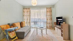 A living room with a sofa, a coffee table, a television, and a baby stroller.