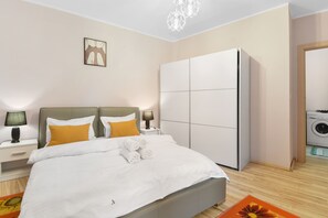 A neatly arranged bedroom with a bed, nightstands, a wardrobe, and a washing machine. - Matteri (Sinaia)