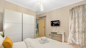 A hotel room with a bed, a TV mounted on the wall, a desk, and a wardrobe.