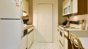 A compact kitchen with a refrigerator, microwave, stove, and wooden cabinets. - 2 Bedroom 2 Bath outdoor pool (Ocean City)