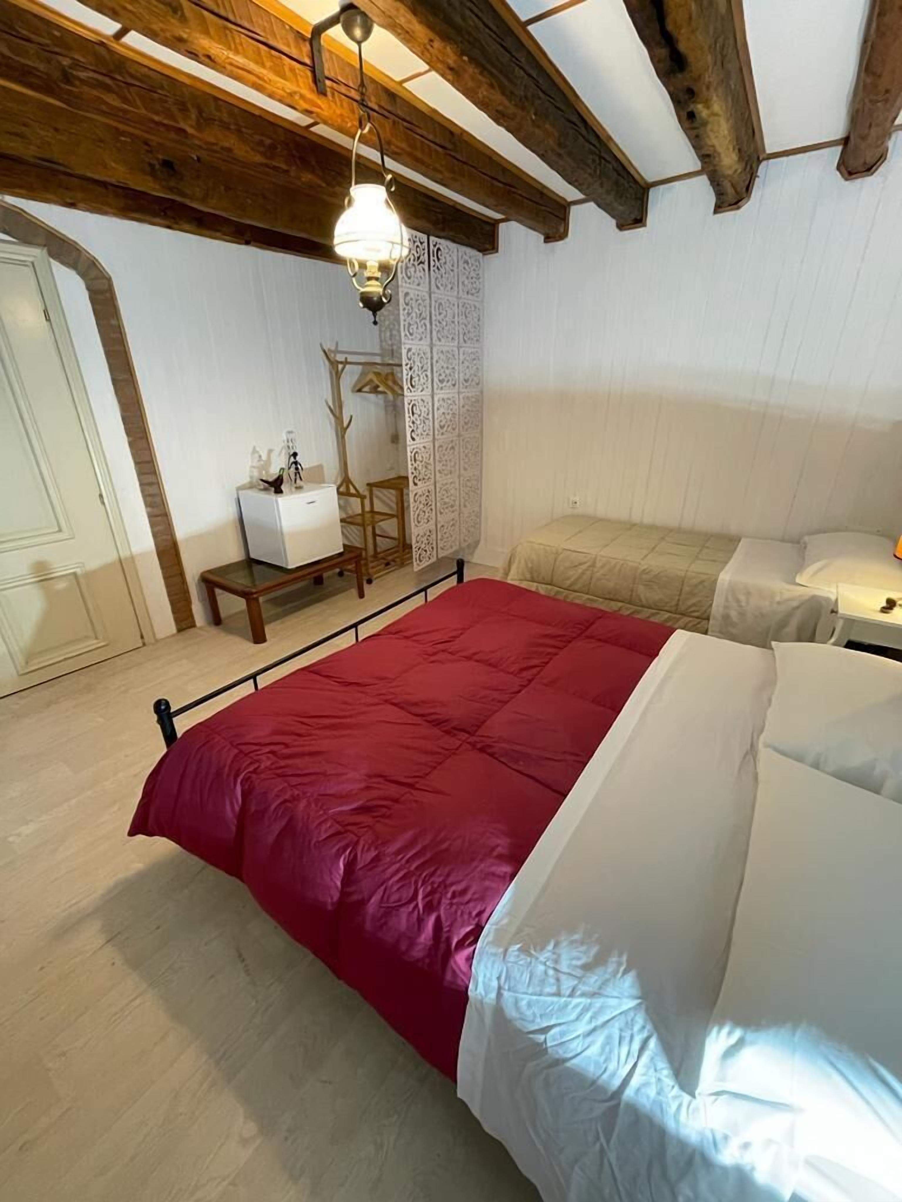 A bedroom with a large bed, a bedside table, a hanging light fixture, and a decorative panel.