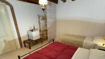 A bedroom with a large bed, a bedside table, a hanging light fixture, and a decorative panel.