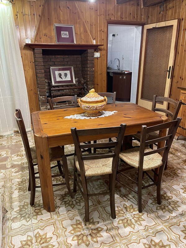 A wooden dining table with a decorative centerpiece, surrounded by wicker chairs. - King's Garden (Venice)