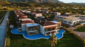 A resort with multiple villas, a central swimming pool, and a mountainous backdrop. - Almyros Beach Resort & SPA (Corfu)
