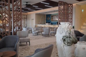 A modern lobby with a bar area, seating arrangements, and decorative elements. - Almyros Beach Resort & SPA (Corfu)