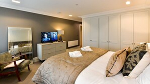 A hotel bedroom with a large bed, a TV, a dresser, a chair, and a wardrobe. - Beautiful 2 Bed Apartment with Parking in the Bay - Pass the Keys (Cardiff)