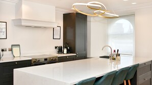 A modern kitchen with a large island, dark cabinetry, and a pendant light. - Beautiful 2 Bed Apartment with Parking in the Bay - Pass the Keys (Cardiff)
