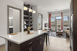 Enjoy dining or socializing at the kitchen's sleek countertop with integrated bar stools and a shelving unit.