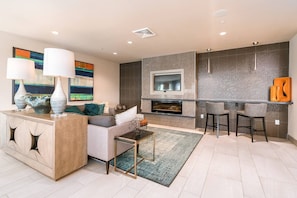 Relax in a spacious living area with a central fireplace, bar, and comfortable seating options.