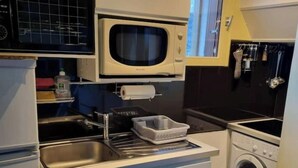 Kompakti keittiö, jossa on mikroaaltouuni, pesuallas ja pyykinpesukone.