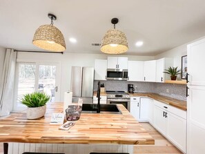 A modern kitchen with a wooden island, stainless steel appliances, and woven pendant lights.