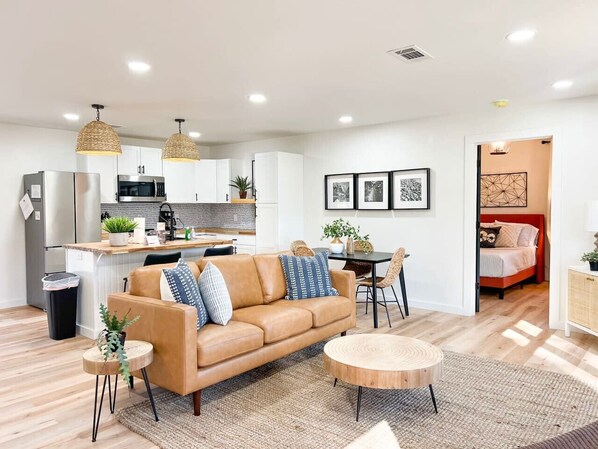 A modern living room with a sofa, coffee table, and dining area.