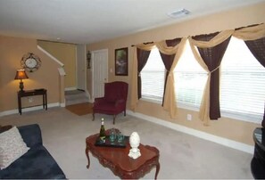 A living room with a sofa, armchair, coffee table, and a staircase in the background. - Enjoy Vacation in a Quiet Area w/ Huge Backyard! (Crosby)