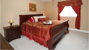 A bedroom with a bed, a nightstand, a lamp, a ceiling fan, and a window with curtains. - Enjoy Vacation in a Quiet Area w/ Huge Backyard! (Crosby)