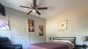 A bedroom with a bed, a ceiling fan, a chair, a nightstand, and artwork on the walls. - Beautiful, spacious one bedroom apartment. (Clearwater)
