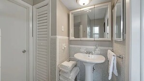 A bathroom with a white sink, a mirror above it, and a towel rack with folded towels. - Beautiful, spacious one bedroom apartment. (Clearwater)