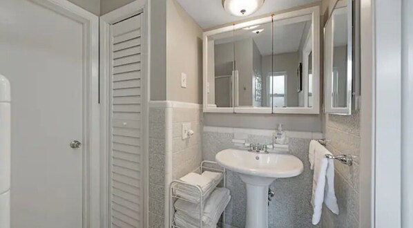 A bathroom with a white sink, a mirror above it, and a towel rack with folded towels. - Beautiful, spacious one bedroom apartment. (Clearwater)
