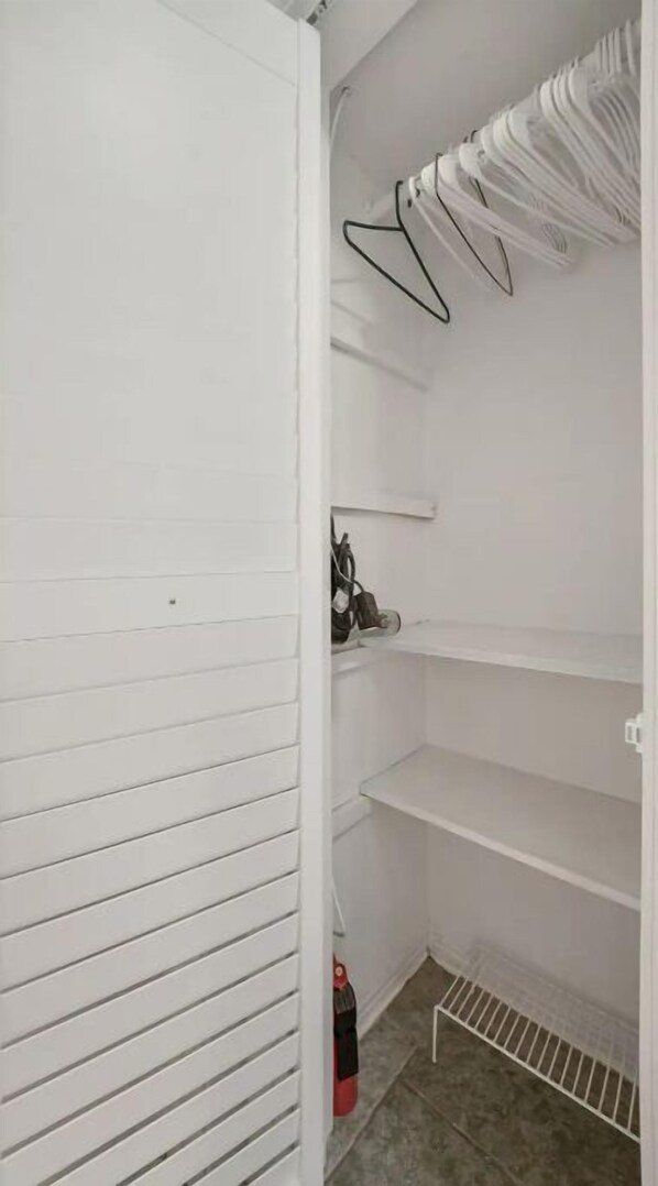 A white closet with sliding doors, a shoe rack, and a fire extinguisher. - Beautiful, spacious one bedroom apartment. (Clearwater)