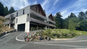 Un edificio moderno a più piani con garage, immerso in un paesaggio roccioso e una fitta foresta.