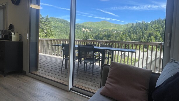 Una stanza con una porta vetrata scorrevole che si apre su una terrazza esterna con tavolo e sedie.