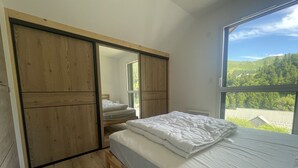 Camera da letto con un'ampia finestra, un'armadio in legno e un letto con biancheria bianca.