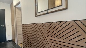 Un corridoio con parete rivestita in legno, uno specchio e una porta.
