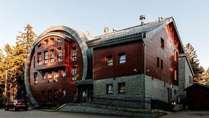 Ein Gebäude mit einer markanten, geschwungenen Fassade, zahlreichen Fenstern und einem steinernen Sockel.