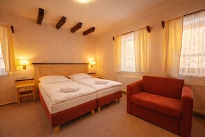 A hotel room with two beds, a red armchair, bedside lamps, and a window with curtains. - Hotel Obří Sud (Dlouhý Most)
