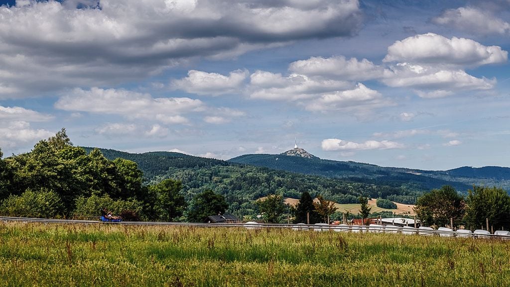 Paisaje con montaña, árboles y cielo despejado.