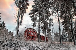 Un edificio rojo rodeado de altos árboles cubiertos de nieve.