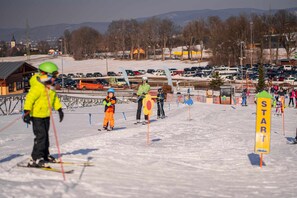 A ski slope with a start sign, a ski lift, and a parking area in the background. - Hotel Obří Sud (Dlouhý Most)
