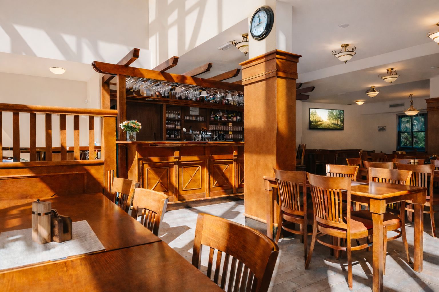 A restaurant with wooden furniture, a bar area, and a clock on the wall.