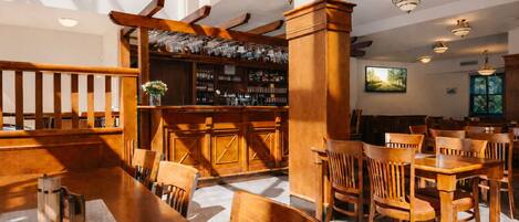 A restaurant with wooden furniture, a bar area, and a clock on the wall.