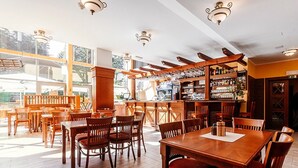 Ein Restaurant mit Holztischen, einer Bar und großen Fenstern.