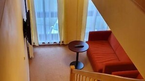 Eine Holztreppe führt zu einem roten Sofa und einem kleinen runden Tisch.