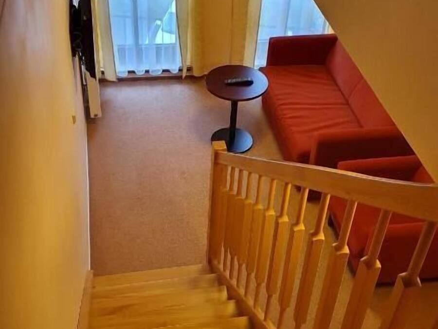 A wooden staircase leading to a red sofa and a small round table.