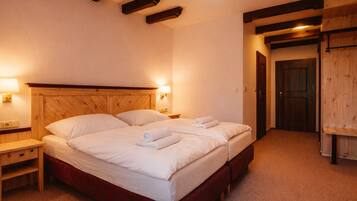 A double bed with two pillows, a wooden headboard, bedside tables, and a wooden wardrobe.