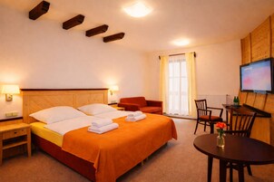 A hotel room with a bed, a desk, a chair, and a TV.