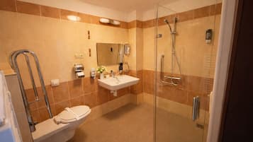 Un baño moderno con ducha envuelta en vidrio, un lavamanos blanco y un inodoro.