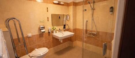 A modern bathroom with a glass-enclosed shower, a white sink, and a toilet.
