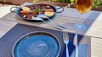 Una mesa con un plato azul, una jarra de cerveza y una fuente de comida.