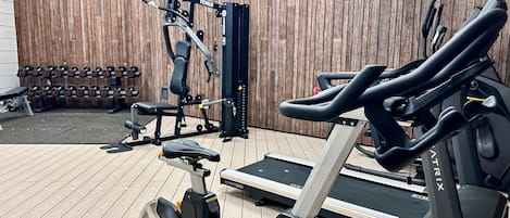A gym with a treadmill, stationary bike, and weight machine.