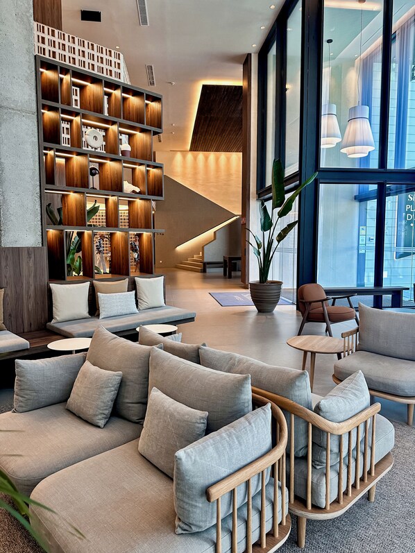 A modern interior with a central staircase, seating areas, and a large window providing natural light. - Silken Platja d'Aro (Castell-Platja d'Aro)