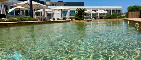 En säsongsöppen utomhuspool, parasoller och solstolar