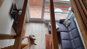 A modern living room with a wooden staircase, a grey sofa, and a small table. - Apartment Seebrücke Schönberger Strand, bright and friendly, dog is welcome (Schönberg)