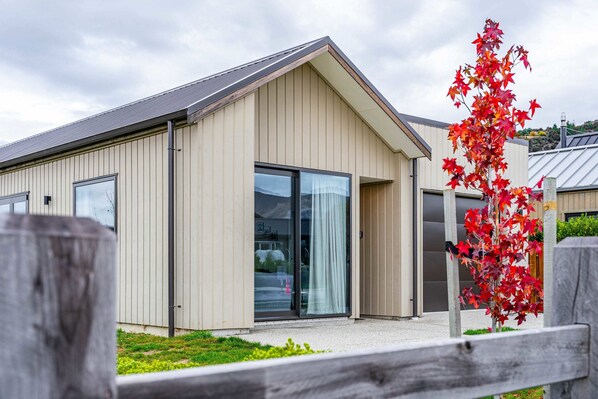 A modern building with a large glass door and windows, a sloped roof, and a wooden fence in the foreground.